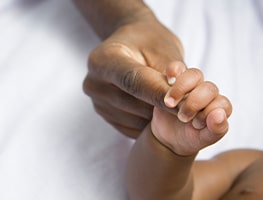 Baby hand holding an adult finger