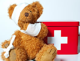 Bandaged teddy next to a first-aid box