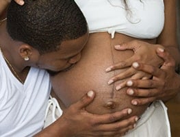 Dad-to-be kissing his pregnant partner's belly