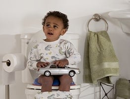 Toddler sitting on the toilet with a toy car