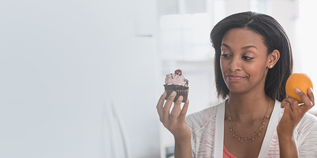 Pregnant woman giving a cupcake a sideward glance
